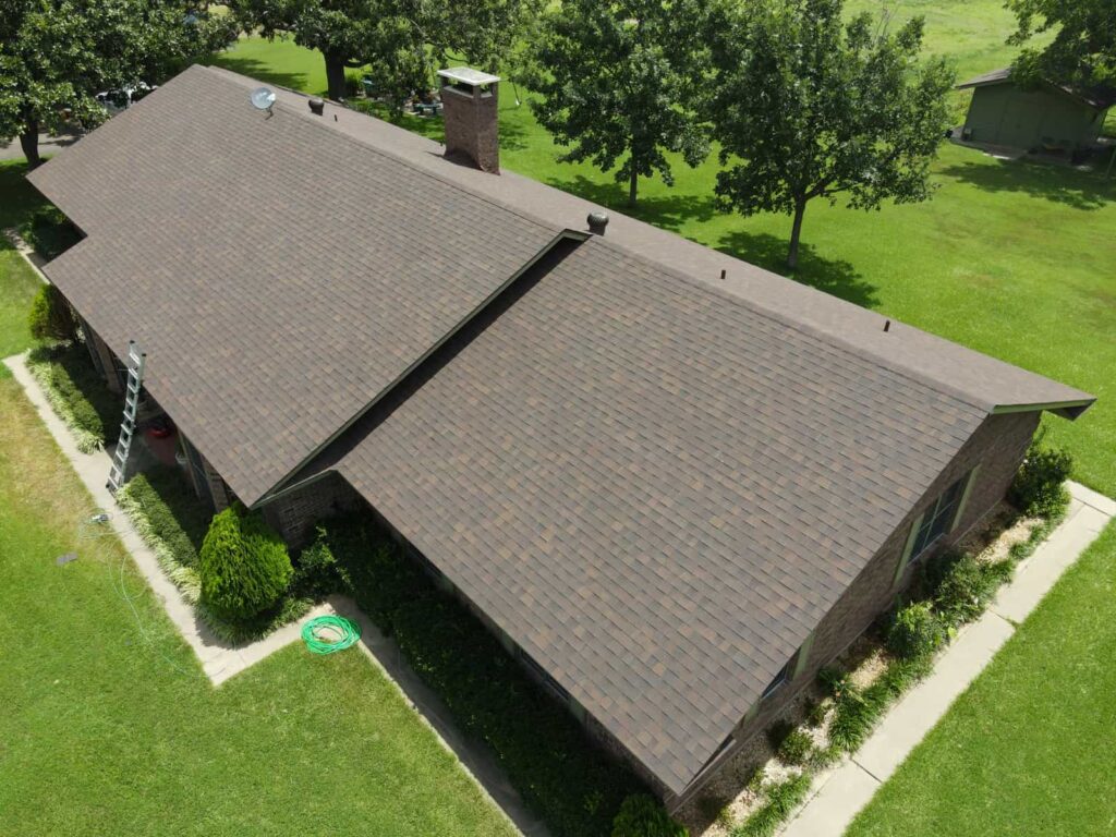 Aerial view of a long ranch home with a grey architectural shingle roof