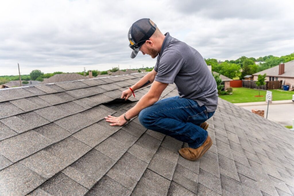 Our Services 7 Roof inspector examining asphalt shingles and taking notes