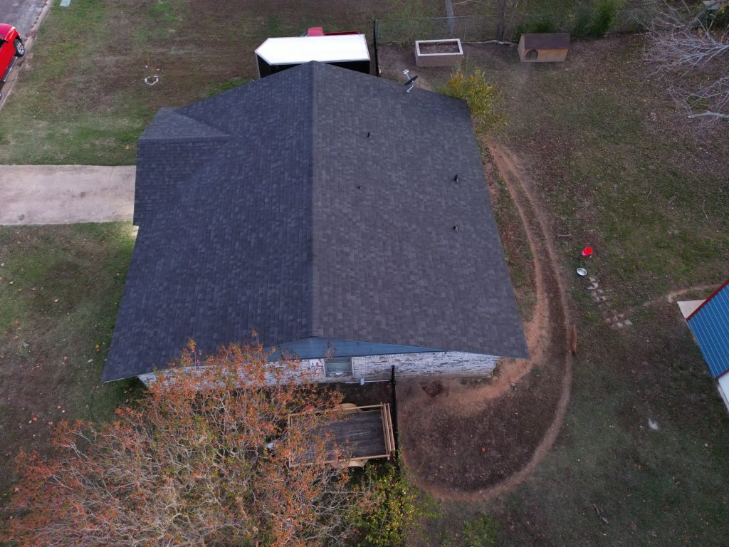 Aerial view of a dark shingle roof on a ranch house with an attached carport