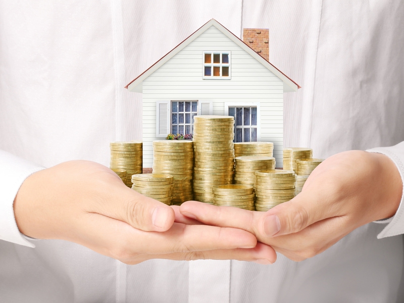 Roof Financing 1 Model house on stacks of coins, illustrating the value a roof adds to a home
