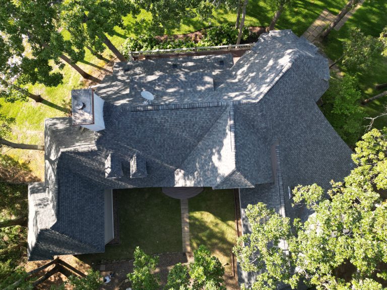 Aerial view of a completed grey shingle roof on a home among trees