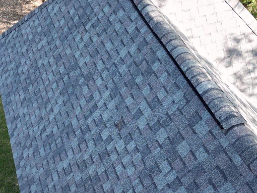 Close view of a gray architectural shingle slope meeting the ridge